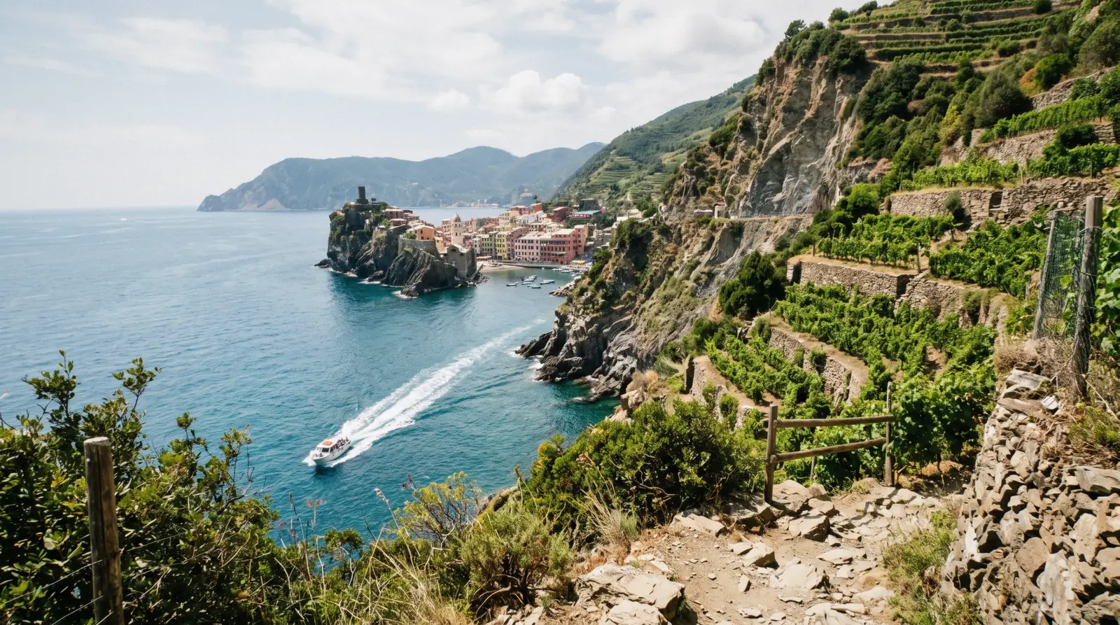 A small tour boat along the Cinque Terre coast below terraced vineyards, Italy