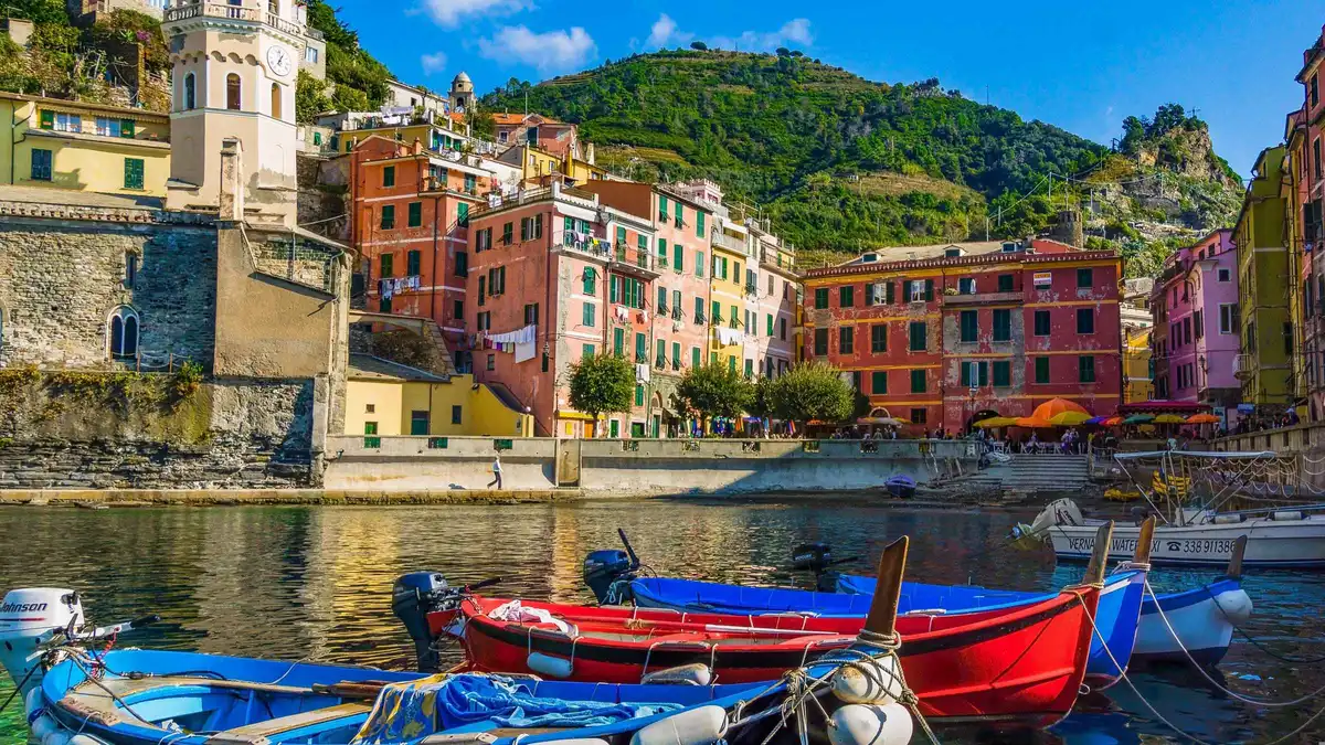 Small motorboat with passengers cruising the Cinque Terre coastline near Monterosso at sunset